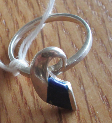 Silver ring with dark stone pendant on wooden surface, front view