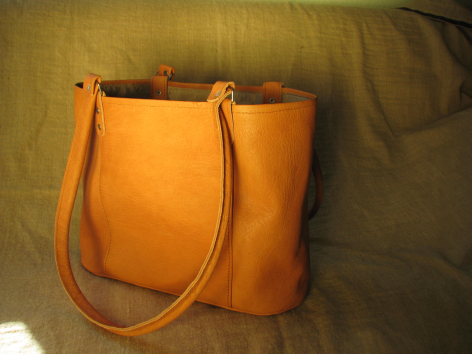 Sac à main en cuir orange vif de forme rectangulaire avec anses assorties, vue de face sur fond neutre