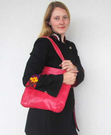Woman wearing black blazer holding bright pink quilted shoulder bag with gold accents