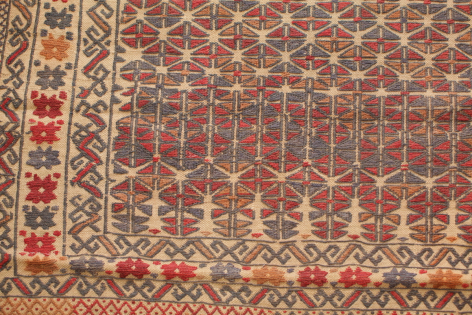 Red and gold woven textile with geometric diamond pattern and decorative border, flat lay view