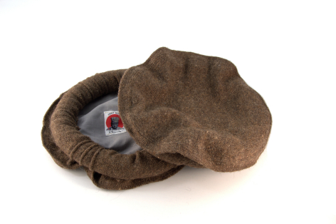 Pochette en cuir marron clair, vue de trois quarts, avec rabat ondulé et détail de fermeture circulaire