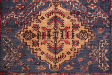 Handwoven Afghan textile with geometric diamond pattern in cream, rust, and deep blue tones, overhead flat lay view