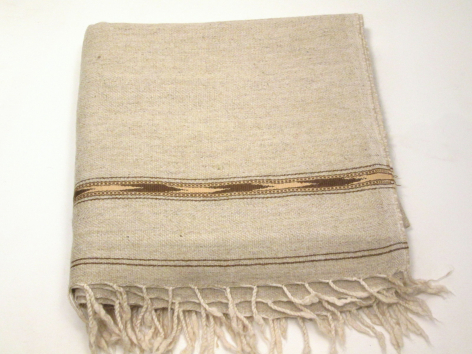 Tissu beige plié avec bande brune centrale et franges effilochées aux extrémités, vue de dessus