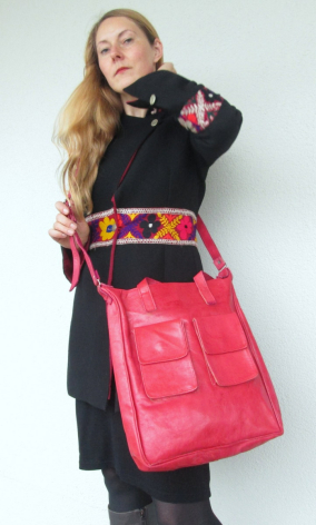 Woman in black top holding bright pink quilted leather tote bag with embroidered details