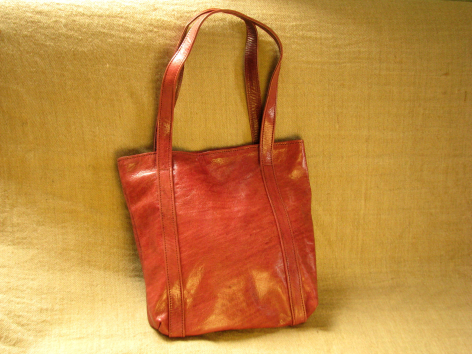 Red and gold silk tote bag with dual handles, front view against golden background