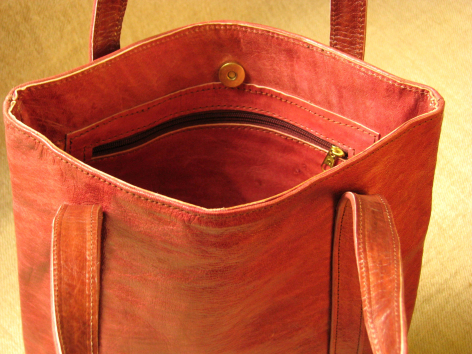 Red leather tote bag open, showing interior lining with reinforced handles and structured sides, viewed from above