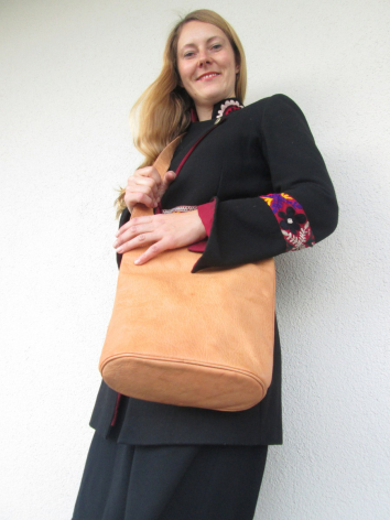 Femme portant un sac à bandoulière en cuir camel avec rabat, vue de face