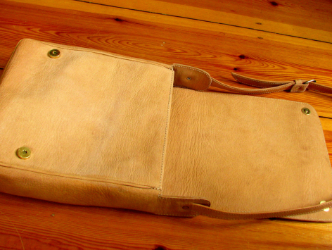 Portefeuille en cuir beige ouvert montrant les compartiments intérieurs, vue de dessus sur surface bois