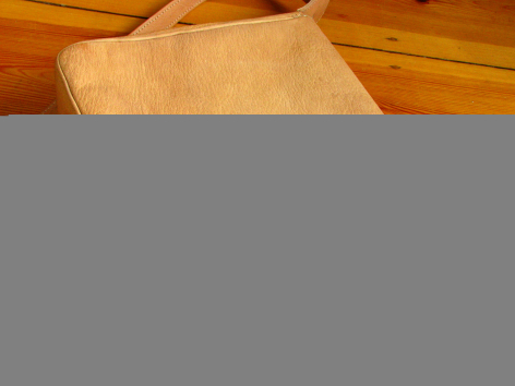 Hellbraune Ledertasche mit gefaltetem Oberstoff, Draufsicht auf Holzuntergrund
