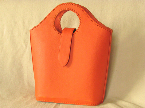 Bright orange leather tote bag with rounded silhouette and dual handles, front view