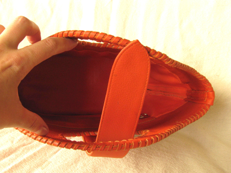 Sac en cuir rouge vif vue de dessus, ouvert, montrant l'intérieur et une anse orange
