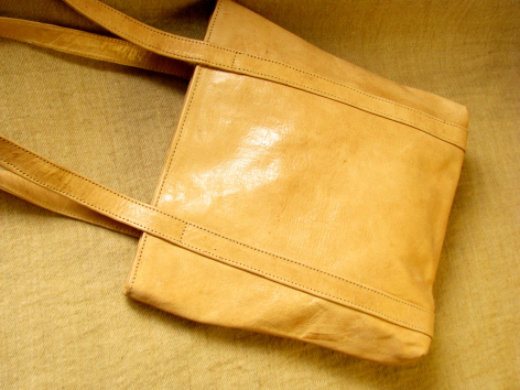 Tan leather crossbody bag with front flap pocket, displayed flat from above showing structured rectangular shape