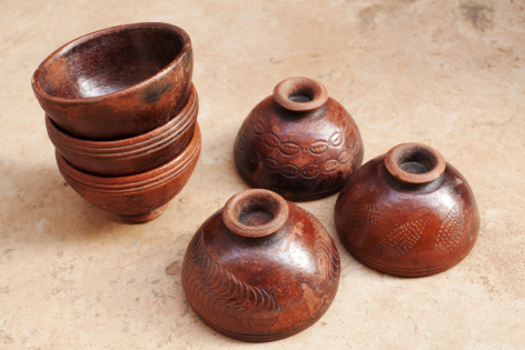 Four wooden bowls and vessels in warm brown tones, stacked and grouped to show rounded forms and hand-turned details