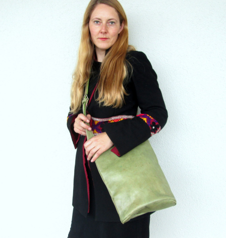 Woman wearing black cardigan holding lime green leather shoulder bag with pink strap detail
