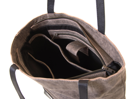 Gray linen tote bag open showing black interior compartments and dark handles, overhead view