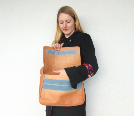 Frau hält zwei cognacfarbene Ledertaschen mit Sichtfenstern, Vorderansicht vor weißem Hintergrund