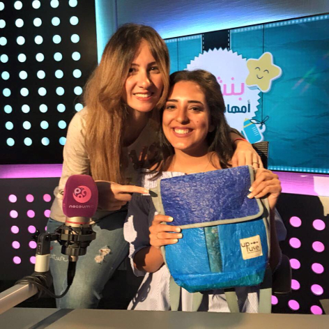 Two women posing together in a studio setting with blue backdrop and illuminated white dot panels behind them
