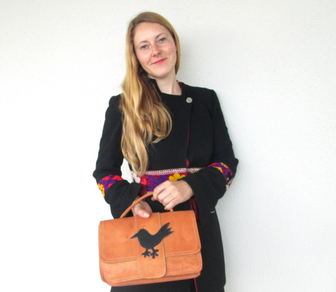 Frau trägt braune Ledertasche mit gestepptem Muster und schwarzem Blazer, Vorderansicht