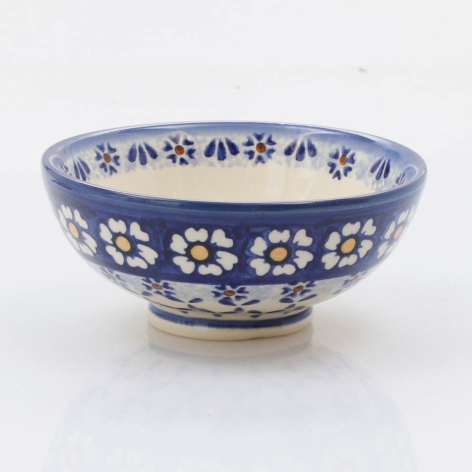 Blue ceramic bowl with white floral pattern, wide shallow form with curved sides, front three-quarter view