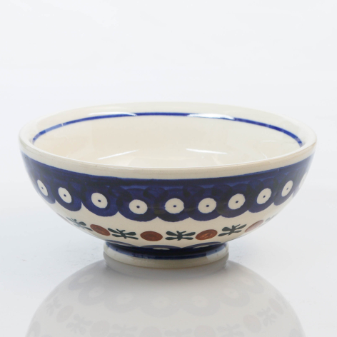 Navy ceramic bowl with cream interior and white polka dot pattern around the exterior, front view