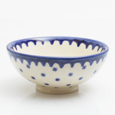 Cream ceramic bowl with blue decorative rim and dotted pattern, shallow rounded form viewed from above