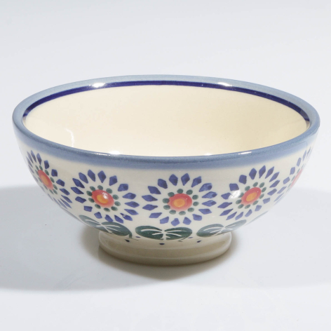 Cream ceramic bowl with blue rim and blue floral pattern featuring red flower accents, front view