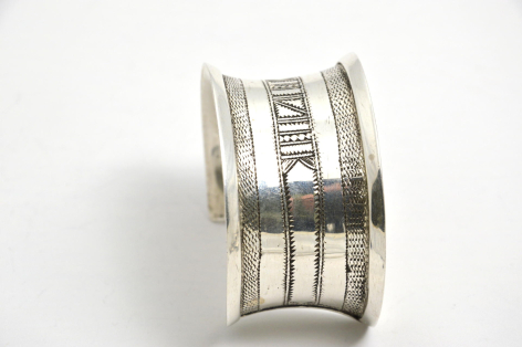 Bracelet argenté ouvert vue de face avec motifs géométriques gravés et détails texturés sur la surface intérieure