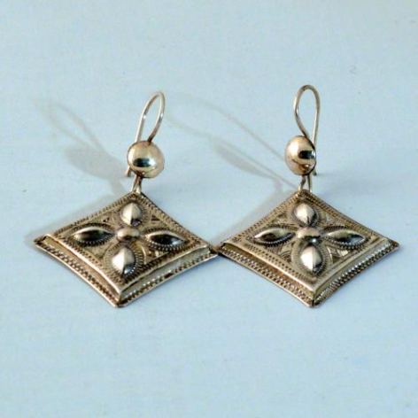 Brass diamond-shaped earrings with geometric patterns and pearl accents on light blue background