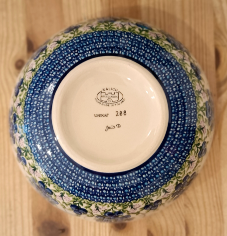 Blue ceramic bowl with cream interior viewed from above, showing maker's mark and production details on base