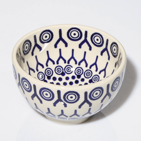 Cream ceramic bowl with blue concentric circle motifs and decorative fan pattern, overhead view