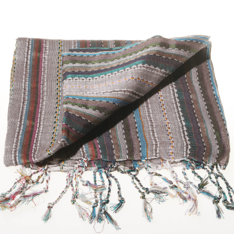 Folded striped textile wrap in earth tones with tasseled fringe ends, showing woven patterns in burgundy, blue and cream