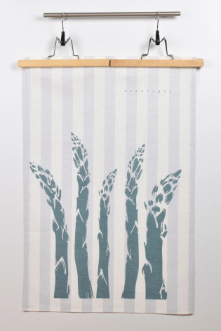 White linen textile with blue-green botanical print of tall grass stems, displayed on wooden dowel with metal clips