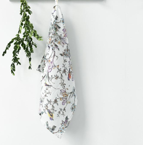 White macramé plant hanger with knotted diamond pattern holding fresh green herb bundle, hanging against neutral wall