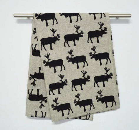 Cream textile with repeating black silhouettes of moose or elk, draped over a horizontal rod, folded view
