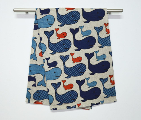 Cream textile with blue and orange whale pattern, folded and displayed on wooden rod