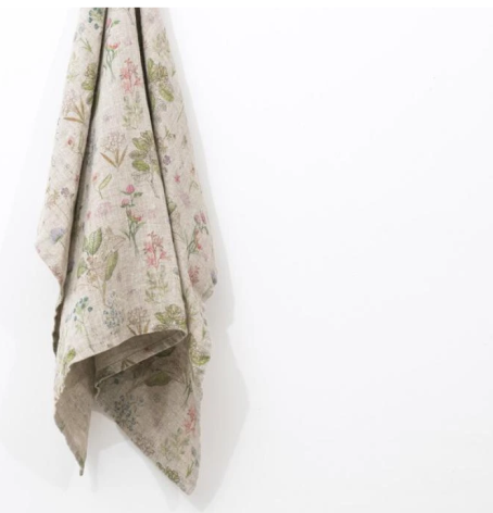 Cream linen textile with faded pink floral pattern hanging draped against white background