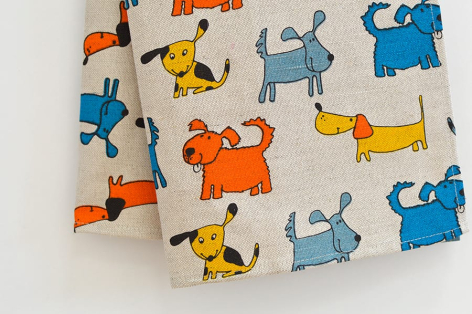 Cream cotton textile with scattered colorful abstract cat and dog illustrations in orange, blue, and yellow throughout