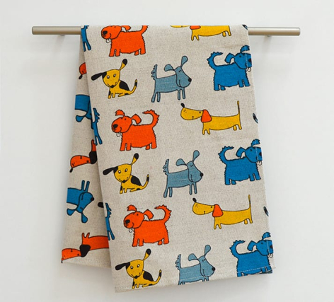 Cream linen textile with colorful cat motif in orange, blue, and yellow, displayed on wooden rod