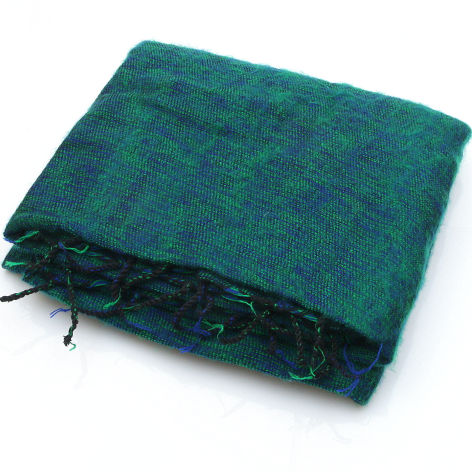 Teal wool textile folded with dark fringe edge, overhead view showing woven texture and natural fiber material