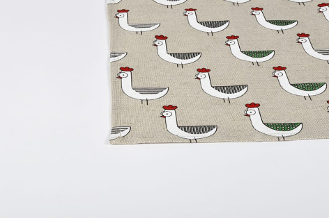 Beige textile with repeating pattern of stylized brown and white birds in flight, angled view showing corner fold