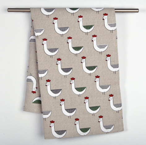 Beige linen textile with repeating white and brown bird motifs, draped over horizontal rod against white wall