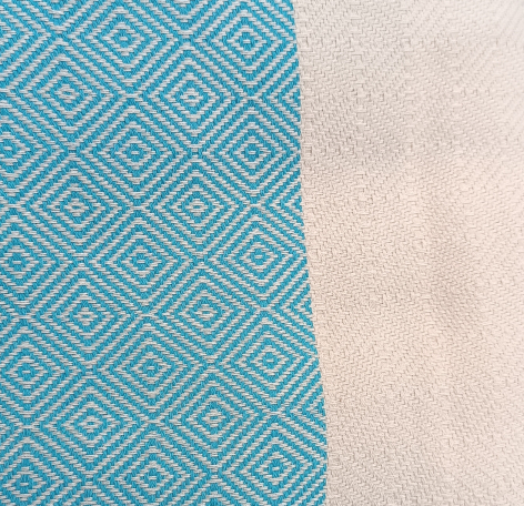 Turquoise textile with geometric diamond pattern beside natural cream-colored woven fabric, flat lay view