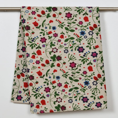 Cream textile with scattered red flowers and green leaves hung on display rod, folded to show pattern