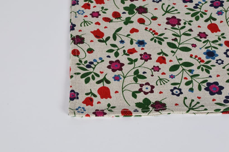 Cream textile with scattered red, green, and black floral pattern, corner fold visible