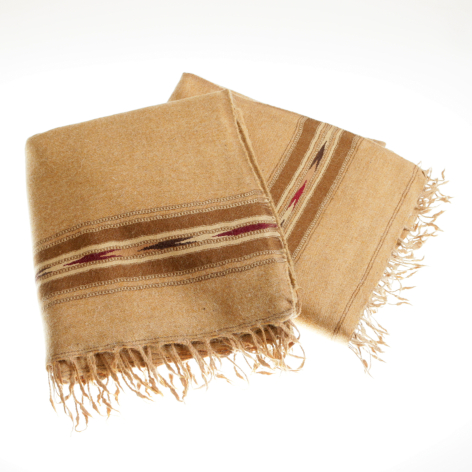 Tan linen textile with striped detail and fringed edges, folded and layered in flat lay view