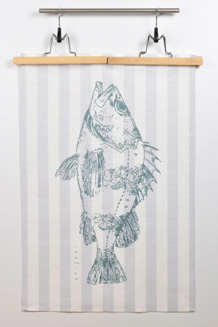 White linen textile with blue geometric fish illustration, displayed on wooden hanging rod with metal clips