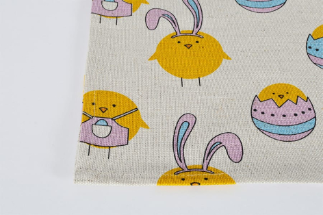 Cream textile featuring illustrated yellow sun and pink striped rabbit ears, folded corner detail, flat lay