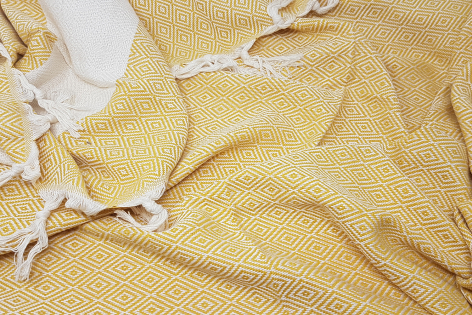 Yellow and cream striped textile with knotted fringe edges, close-up detail view