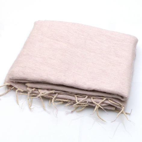Folded pale pink linen textile with fringed edges, three-quarter view showing woven texture and natural fibers