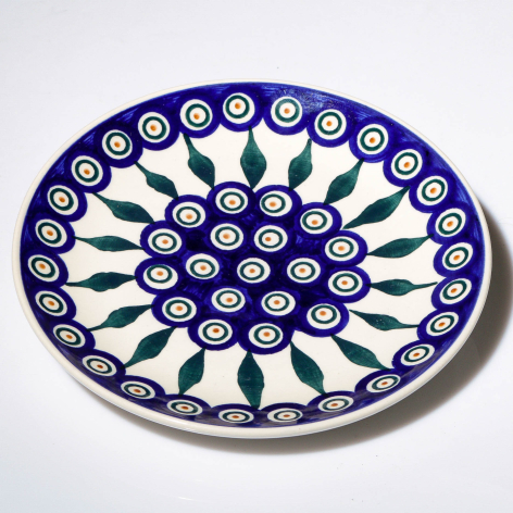 Deep blue and white ceramic plate with radiating hand-painted dot pattern, viewed from above
